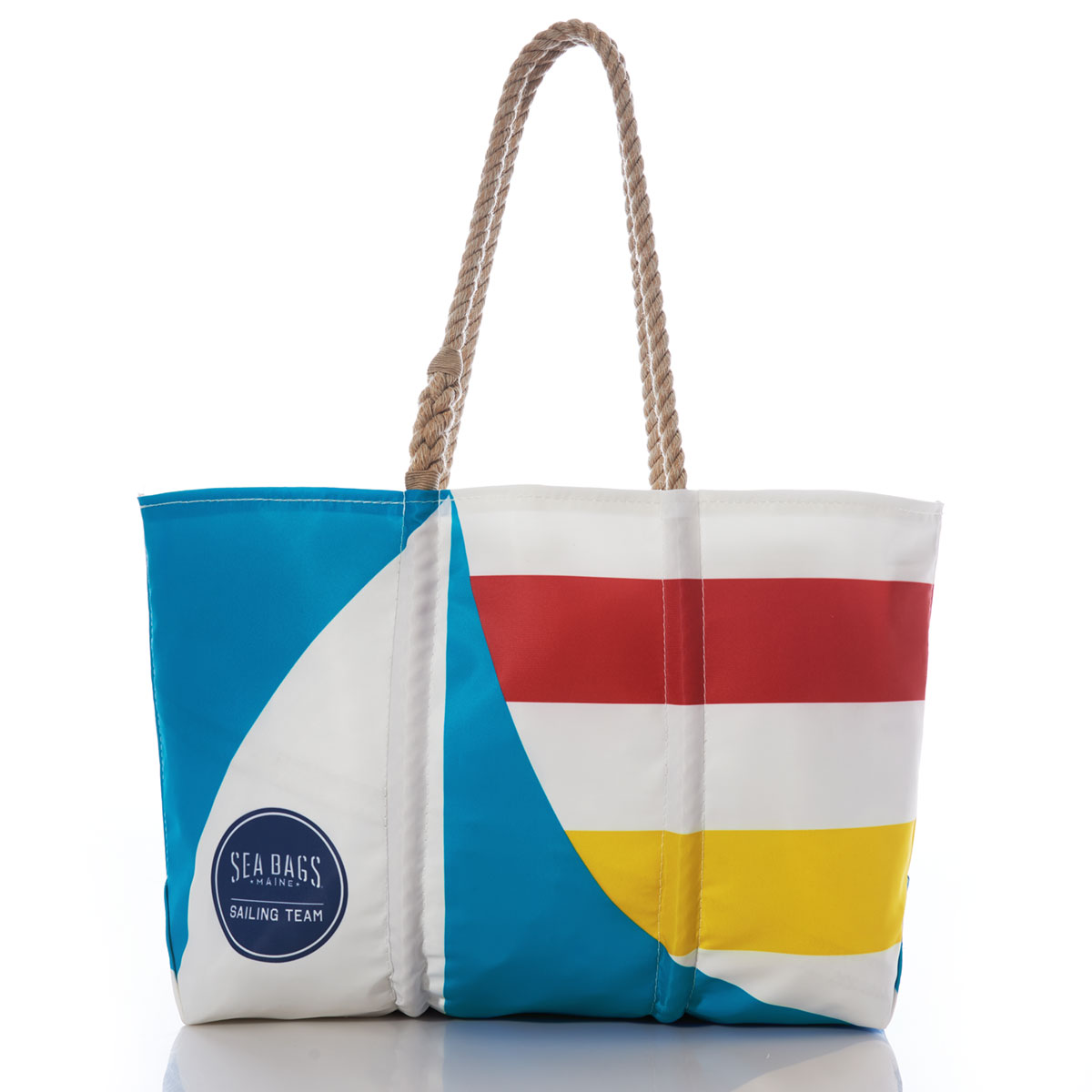 a recycled sail cloth tote with hemp rope handles is printed with a blue graphic sailboat and bold yellow and red stripes and the sea bags womens sailing team circle logo