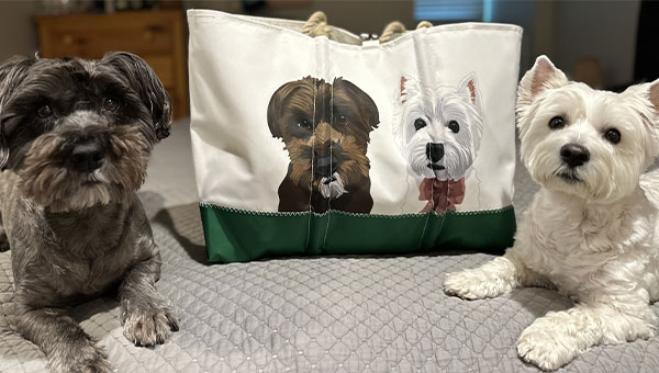 Two dogs sitting in front of a custom dog bag