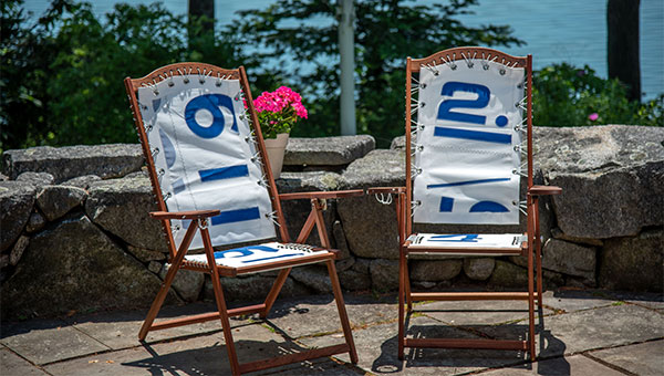 Two vintage lounge chairs on a sunlit patio deck by the water