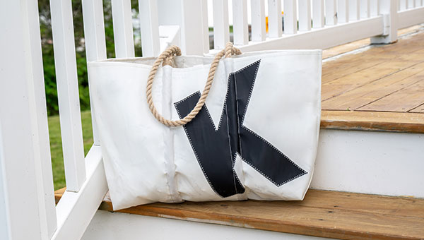 Single letter large tote shown sitting on outdoor stairs