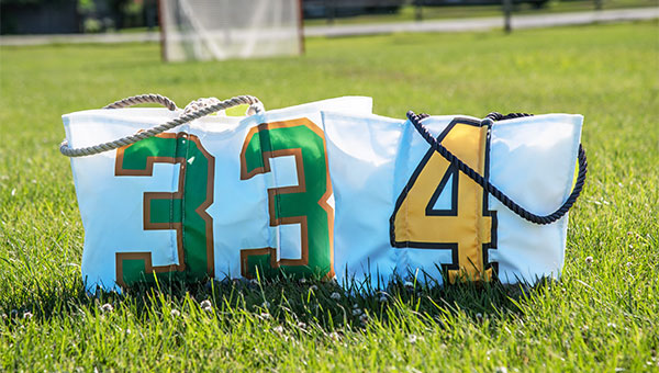 Two different superfan totes sitting in a grass field