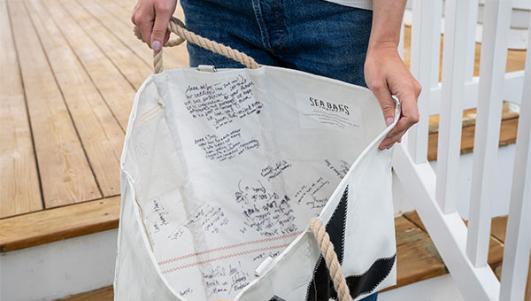 Single letter large tote shown sitting on outdoor stairs