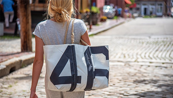 Woman walking down street with large tote hanging over her shoulder