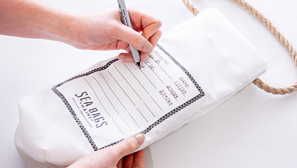 Woman signing backside of a wine bag